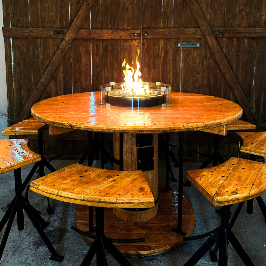 Großer DIY-Bartisch aus alter Holz-Kabeltrommel mit integrierter Gas-Feuerstelle für 8 Personen – rustikales Upcycling Möbelstück von MachNeuWerkstatt