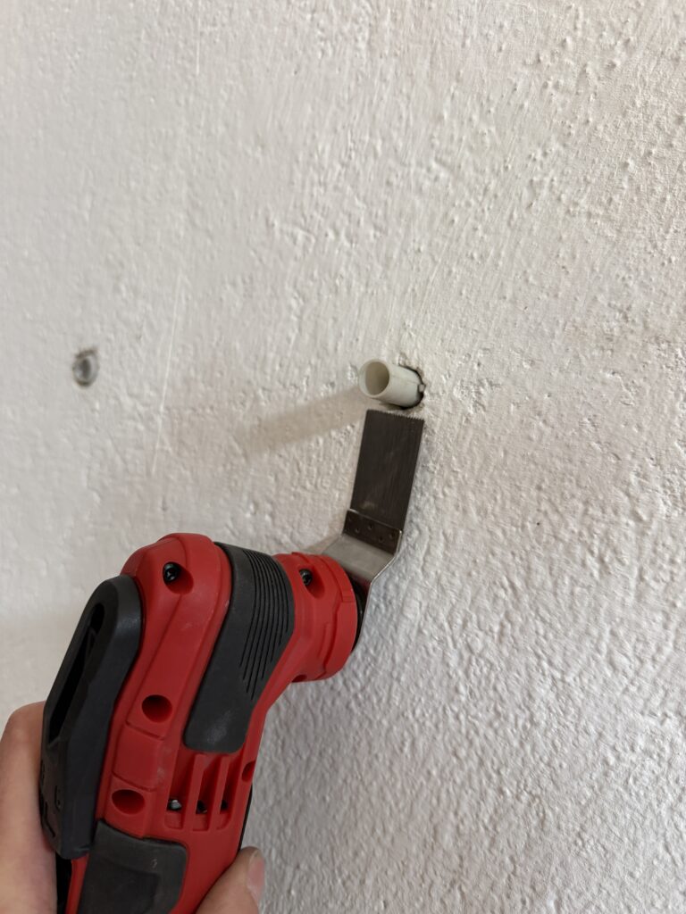 Einhell Varrito Multitool kürzt einen überstehenden Dübel bündig an der Wand
