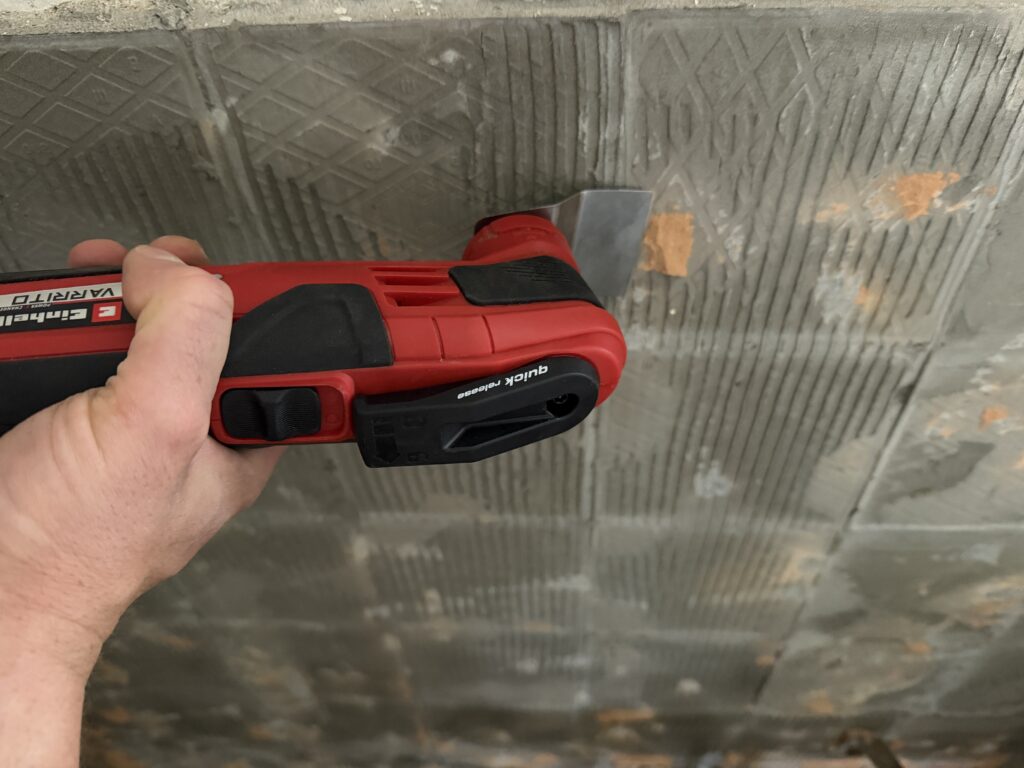 Einhell Varrito Multitool schabt alten Fliesenkleber mit starrem Schaber von der Wand