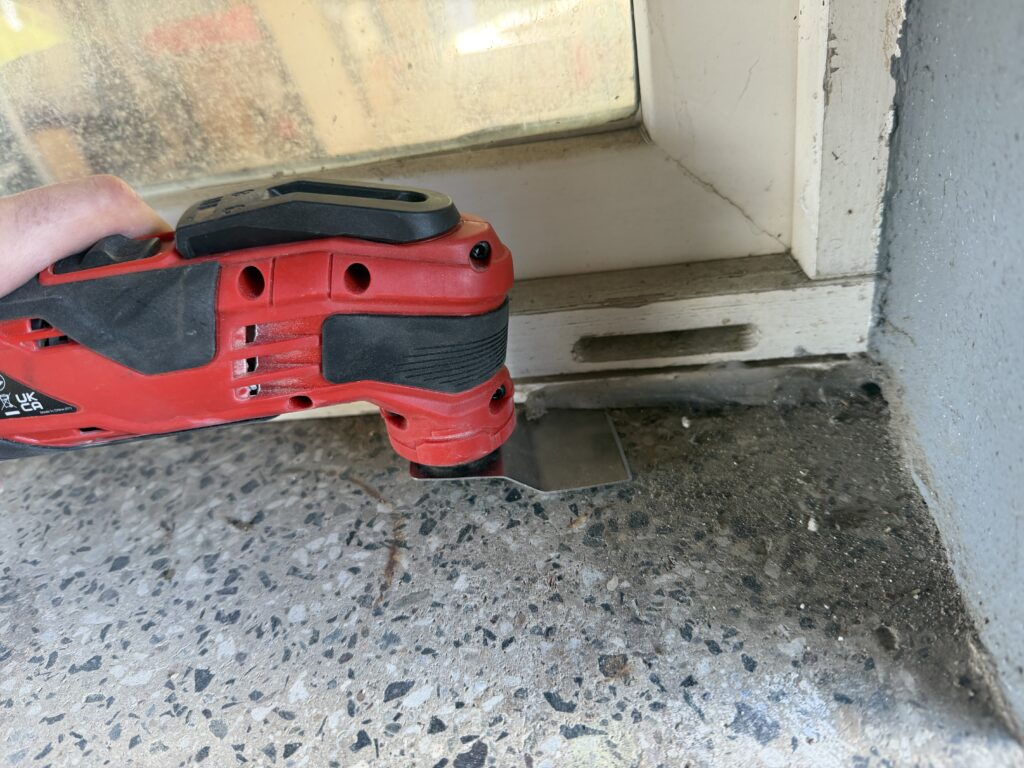 Einhell Varrito Multitool schabt alte Silikonfuge am Fensterrahmen mit starrem Schaber ab