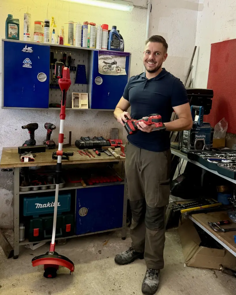 Markus Nowak hält Einhell Power X-Change Akku und Multitool, daneben der Akku-Rasentrimmer – ein Akku für Werkstatt und Garten