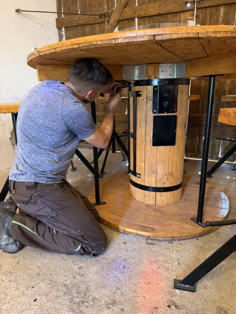 Markus verschraubt mit dem Bosch IXO 7 eine Verbinderplatte an einem Biertisch aus Kabeltrommel
