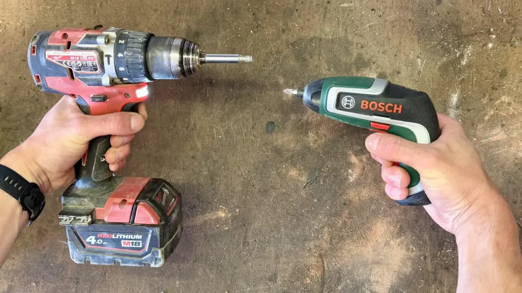 Bosch IXO 7 im Größenvergleich neben einem Milwaukee M18 Akkuschrauber auf der Werkbank
