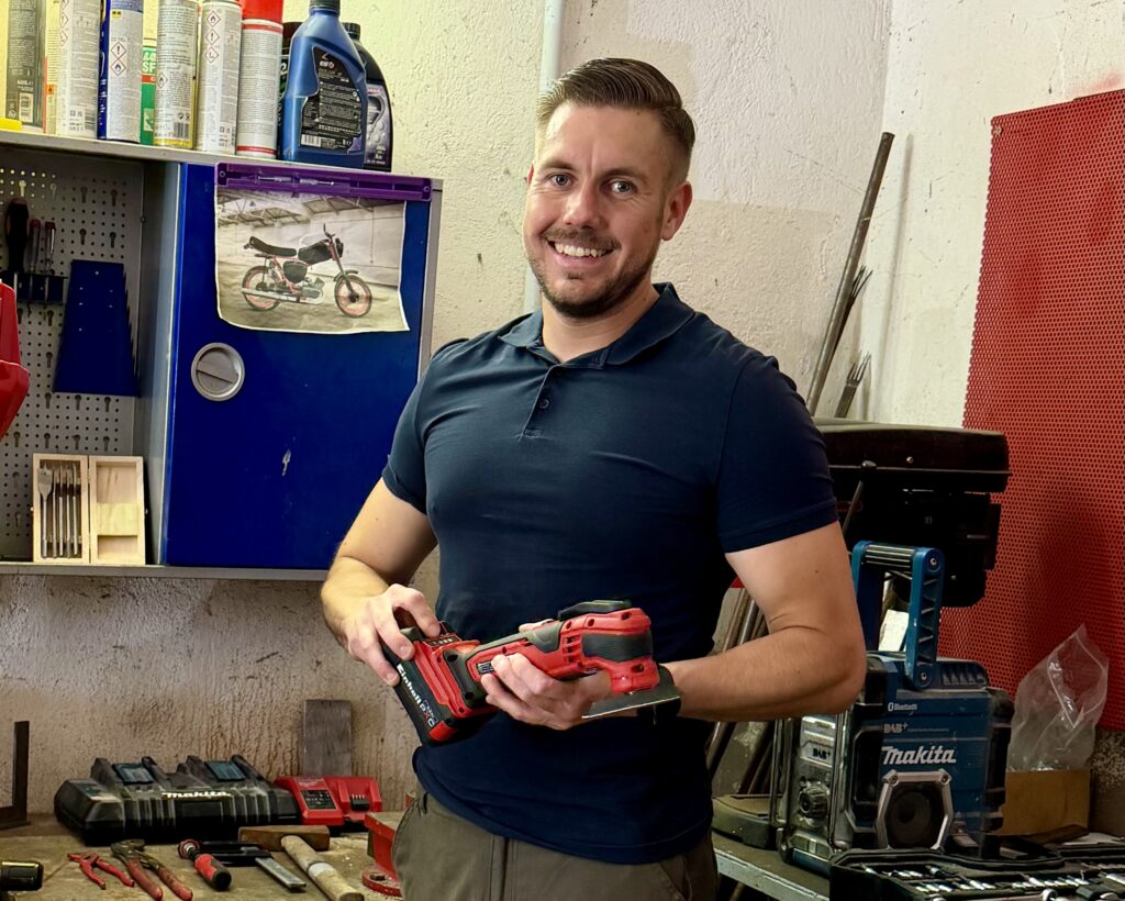 Markus hält den Einhell Varrito 18V beim Praxistest in der Werkstatt in der Hand