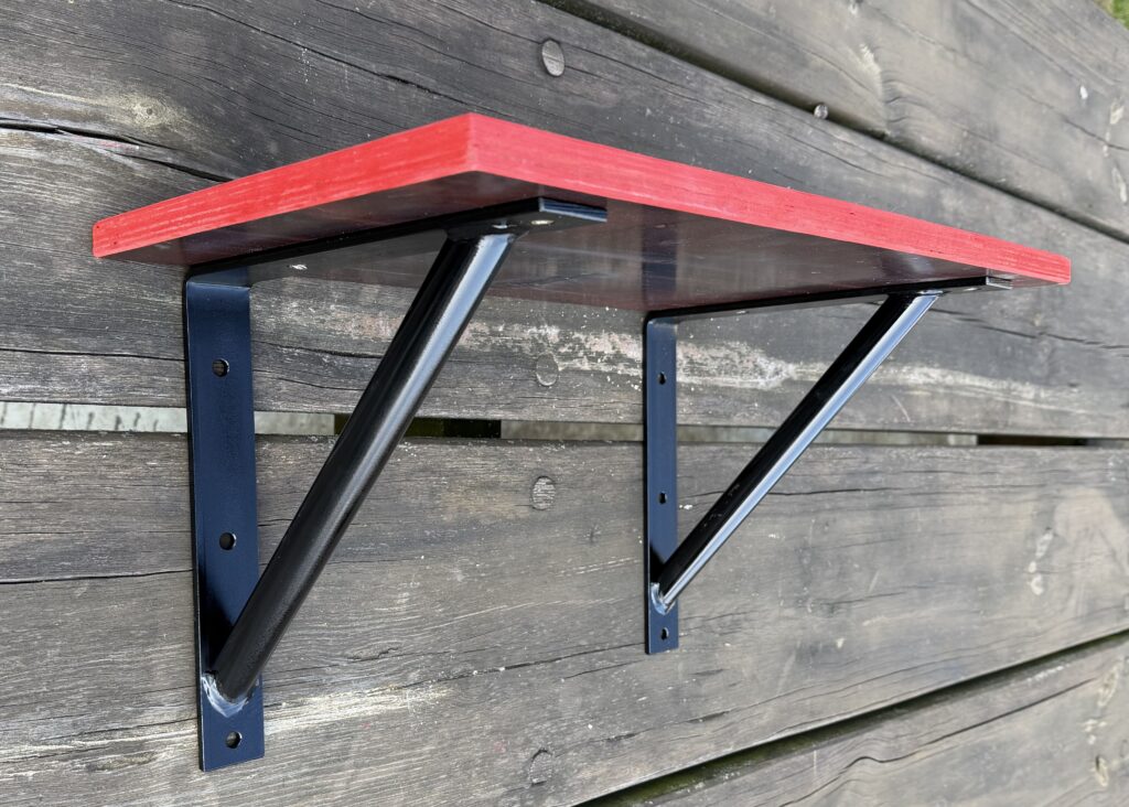 Fertig gebautes Wandregal aus MDF und schwarzen Stahlwinkeln liegt auf einem Tisch und ist bereit zur Montage