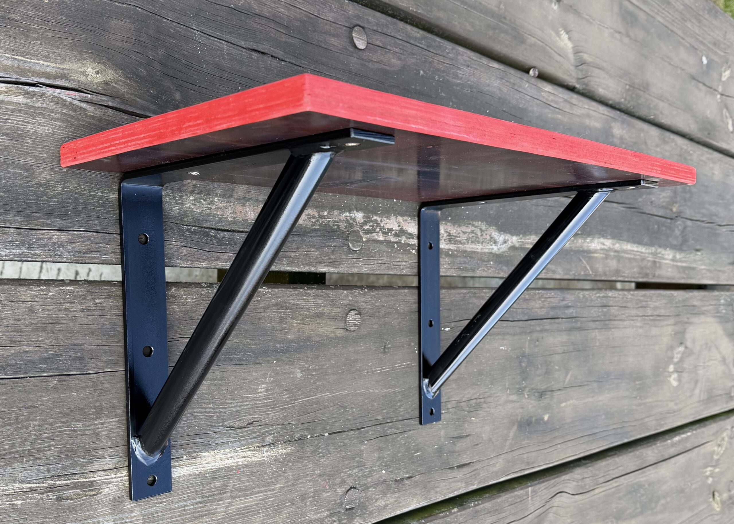 Fertig gebautes Wandregal aus MDF und schwarzen Stahlwinkeln liegt auf einem Tisch und ist bereit zur Montage