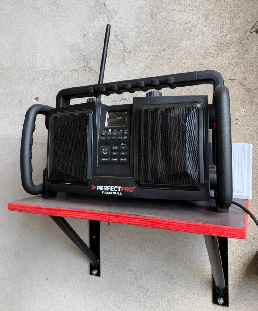 Montiertes Wandregal an der Betonwand mit Baustellenradio PerfectPro Rockbull darauf