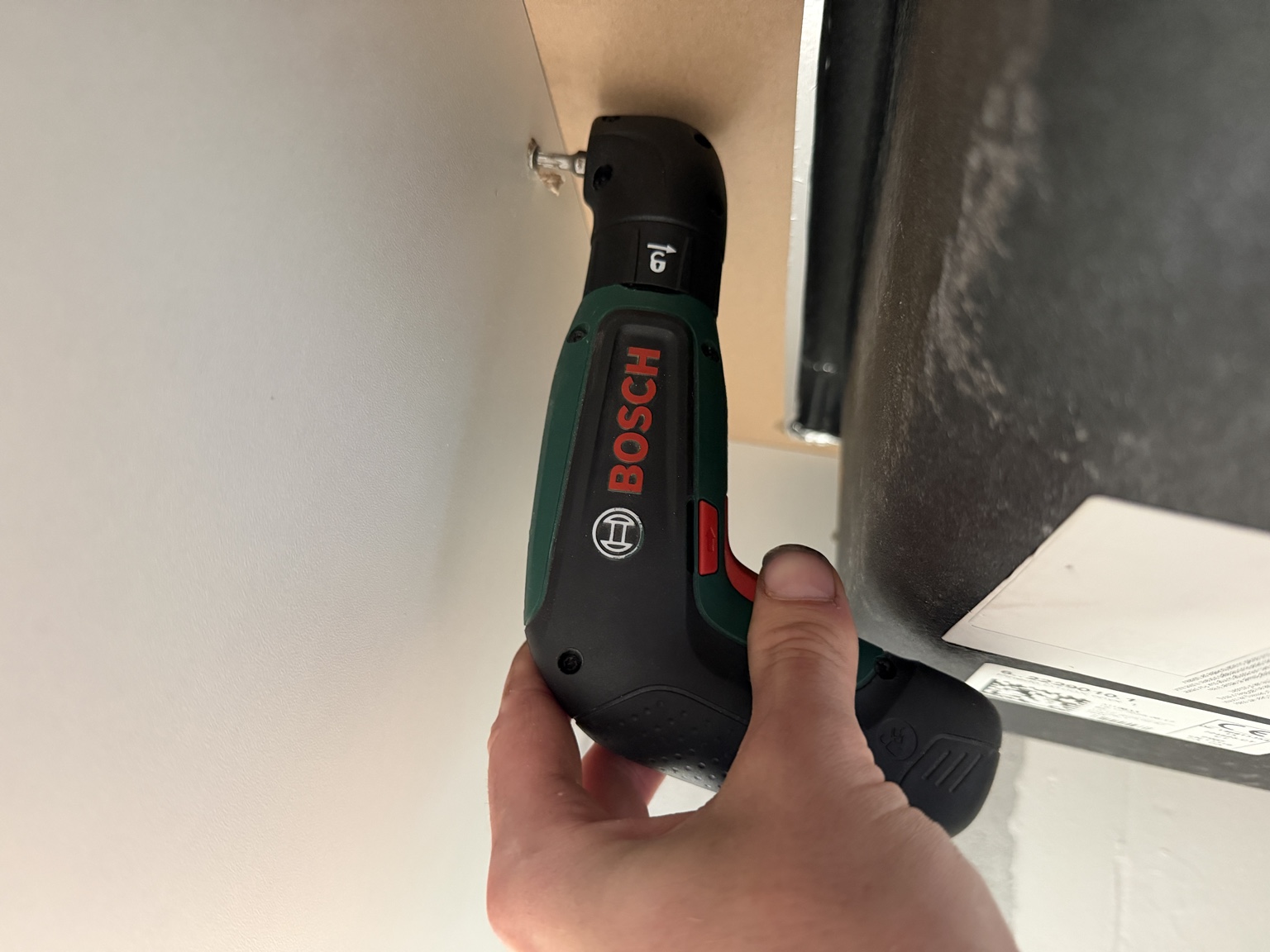 Bosch IXO mit Winkelaufsatz an einer seitlichen Schraube im engen Möbelkorpus