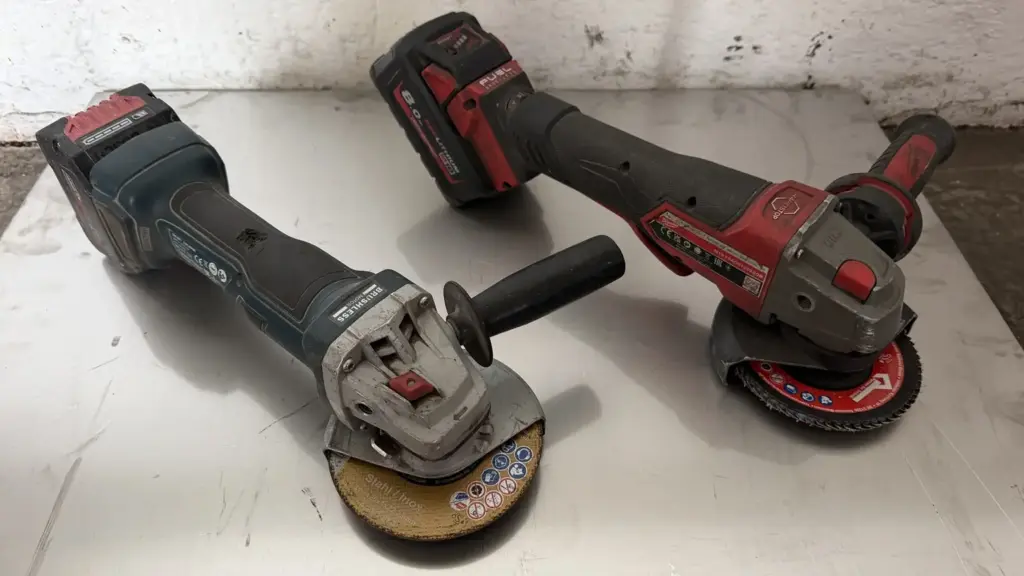 Milwaukee M18 FUEL und Bosch GWS 18V-7 mit 125-mm-Scheiben nebeneinander auf einer Stahlplatte. Milwaukee vs. Bosch Akku-Flex