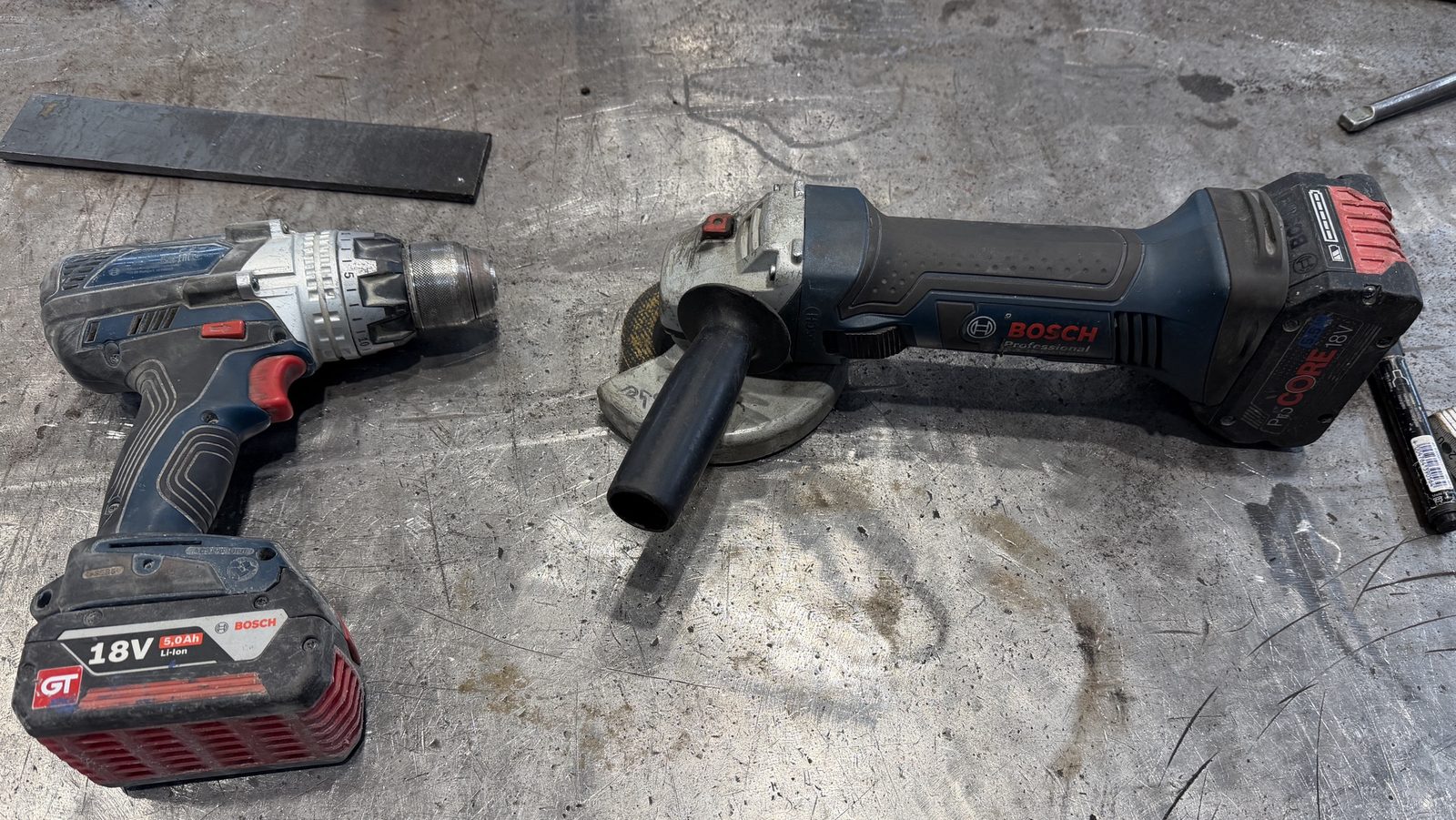 Bosch Professional GSR 18V-110 C und GWS 18-125 V-LI mit 18-V-Akkus auf einem Schweißtisch